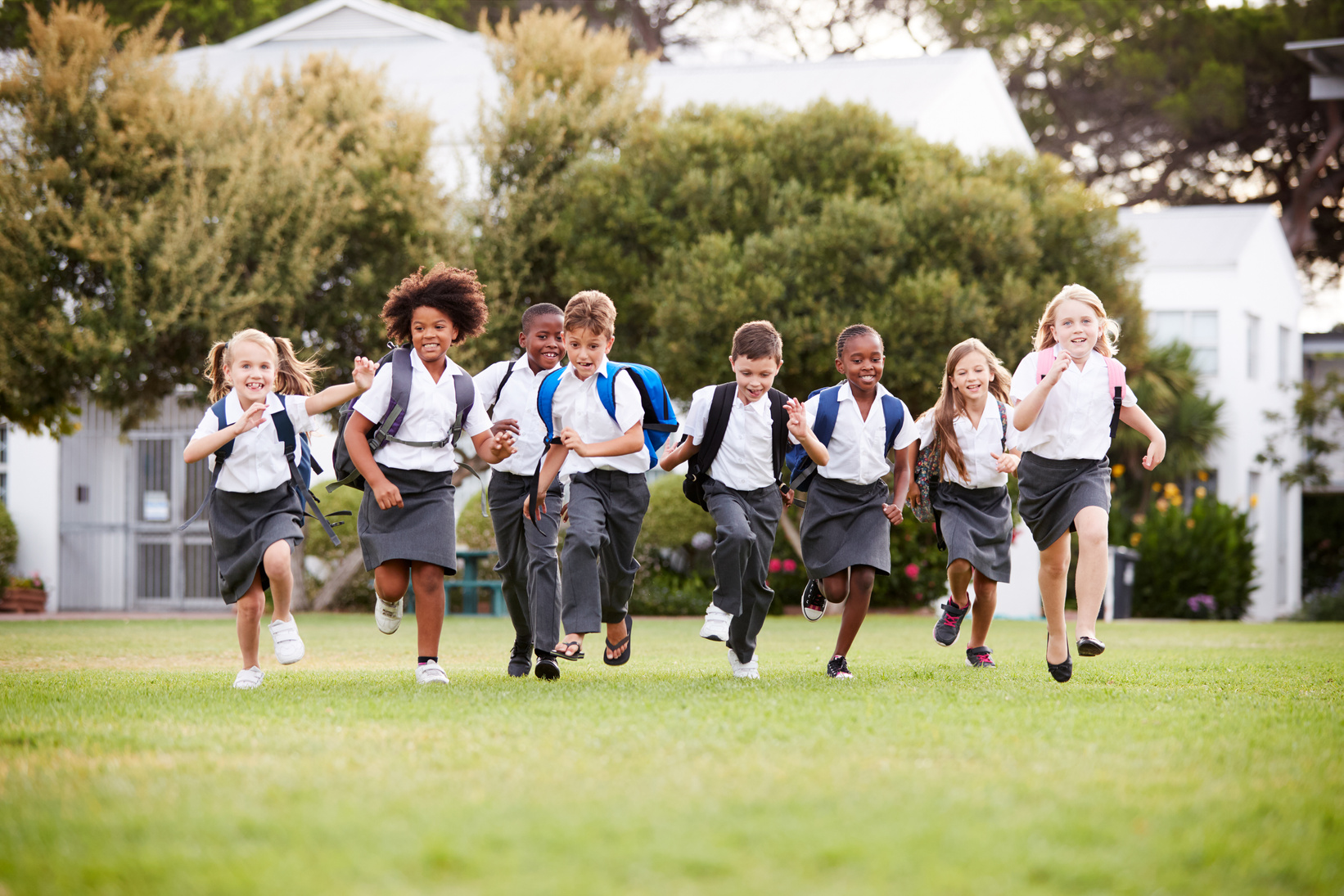 Excited Elementary School Pupils Wearing Uniform Running across